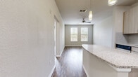 Located at 2650 Dade Ave in Orlando, FL, this one-bedroom, one-bathroom unit offers a well-designed, single-floor layout that maximizes every square foot of its compact footprint. The open-concept kitchen serves as a central highlight, featuring light wood cabinetry, a subway tile backsplash, granite countertops, and a full suite of stainless steel appliances including a range, over-the-range microwave, and refrigerator. A peninsula with additional granite counter space extends into the main living area, providing convenient bar-style seating or meal prep space. Durable hardwood-style flooring runs throughout the kitchen, hallway, and living room, adding warmth and continuity. The living area is bright and airy, with dual windows fitted with blinds that allow natural light to filter in, complemented by a ceiling fan with a pendant light fixture overhead. The bedroom is a comfortable retreat, carpeted for added coziness, with two windows offering natural views and its own ceiling fan. The bathroom is clean and functional, featuring tile flooring, a vanity with modern cabinetry, a large mirror, and a full tub-shower combination. A dedicated closet and hallway complete the efficient, thoughtfully organized floor plan.