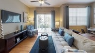 This single-floor residence offers a thoughtfully designed layout that balances comfort and functionality throughout. The open-concept living and dining area is anchored by warm hardwood-style flooring, a ceiling fan, and large sliding glass doors that invite abundant natural light and provide access to an outdoor balcony. A secondary dining nook with a compact table sits adjacent to the living space, making the area ideal for both relaxing and entertaining.

The kitchen features light wood cabinetry, dark granite countertops, and a full suite of black appliances, including a range, microwave, and refrigerator. A peninsula counter connects the kitchen to the living area, creating a seamless flow between spaces. Conveniently located nearby is a dedicated in-unit laundry area with a full-size washer and dryer.

Both bedrooms are generously sized, each outfitted with plush carpeting, ceiling fans, and large windows that frame outdoor greenery. The rooms offer a calm, restful ambiance with ample natural light.

Two bathrooms serve the residence, both showcasing a classic black-and-white octagon tile floor, dark-stained vanity cabinetry, and white countertops. One bathroom features a shower-tub combination, while the other includes a walk-in shower, providing practical versatility for residents.