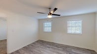 This single-story, one-bedroom, one-bathroom residence offers a thoughtfully designed layout with modern finishes throughout. The living area features light gray wood-look flooring, white walls, and multiple windows with slatted blinds that allow ample natural light to fill the space. A ceiling fan with integrated lighting provides both comfort and functionality. Crown molding accents the upper edges of the living area walls, adding a refined touch.

The kitchen is well-equipped with white shaker-style cabinetry, granite-look countertops, and stainless steel appliances, including an electric range, built-in microwave, and dishwasher. A pendant light above the sink area adds a contemporary aesthetic, while a window above the sink provides natural light.

The bedroom is carpeted for comfort and includes a ceiling fan, a window with blinds, and easy access to the hallway. The bathroom features a granite-topped vanity with an undermount sink, a bold-framed mirror, and a tiled tub-shower combination with marble-style tile surround and chrome fixtures. The overall design is clean, cohesive, and move-in ready.
