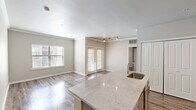Located in the heart of Austin, Texas, this single-story, three-bedroom, two-bathroom residence offers a well-designed layout with modern finishes throughout. Wood-style plank flooring runs continuously across the home, lending warmth and visual cohesion to every room.

The open-concept kitchen and living area serves as the centerpiece of the home. The kitchen features a large island with a striking marble-style countertop and an integrated sink, complemented by gray cabinetry, subway tile backsplash, stainless steel appliances, and track lighting overhead. The adjacent living area is bright and airy, with large windows and French doors that invite natural light and provide outdoor access.

The spacious primary bedroom includes a ceiling fan, a window with exterior views, and direct access to its own closet. The two additional bedrooms also feature wood-style flooring and ceiling fans. Two full bathrooms mirror each other in design, each offering marble-style vanity countertops, wood cabinetry, and a tiled tub-shower combination. Two generously sized closets with wire shelving systems provide ample storage. Crown molding and neutral gray tones throughout complete the clean, contemporary aesthetic of this well-appointed Austin residence.