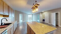 This single-floor residence offers a thoughtfully designed open-concept layout that seamlessly connects the kitchen, dining, and living areas. The kitchen is a standout feature, showcasing warm natural wood cabinetry extending to the ceiling, granite countertops, a large center island with pendant lighting, and a full suite of stainless steel appliances including a refrigerator, range, microwave, and dishwasher. A striking rustic chandelier adds character above the island. Durable wood-look flooring runs throughout the main living areas, complementing the neutral, warm-toned walls that create a clean and inviting atmosphere. The living area is bright and open, with a ceiling fan and large sliding glass doors leading to a private balcony with exterior views. The bedrooms are carpeted for comfort, each featuring natural light from windows with exterior views and ceiling fans. The bathrooms are finished with granite-topped wood vanities, LED-lit medicine cabinets, and wood-look flooring, with a bathtub and shower combination in the full bath. A dedicated in-unit laundry area with a washer is conveniently accessible from the main living space, adding everyday practicality to this well-rounded residence.