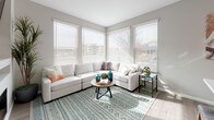 This single-story residence in Sparks, Nevada offers a cohesive modern design with thoughtfully appointed spaces throughout. The living area serves as the heart of the home, featuring corner windows dressed with white horizontal blinds that allow abundant natural light to filter in. A large sectional sofa, wood-framed coffee table, and patterned area rug in soft teal tones create an inviting, comfortable atmosphere with views of the surrounding neighborhood.

The kitchen is outfitted with floor-to-ceiling dark espresso cabinetry, stainless steel appliances including a gas range, over-the-range microwave, and French door refrigerator. A generously sized island with a white quartz countertop and bar seating connects the kitchen seamlessly to the living space. Light wood-look flooring extends throughout the main areas, contributing to a clean, contemporary aesthetic.

The bedrooms each carry distinct character. One features warm terracotta-toned accent walls with plush carpet and a sliding closet, while another showcases bold teal walls with patterned drapes and soft carpeting. The bathrooms include dark vanity cabinetry with white countertops and wood-look tile flooring, maintaining the home's consistent modern style.