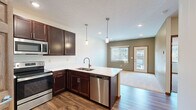 This thoughtfully designed 2-bedroom, 2-bathroom single-floor residence offers a functional and modern layout. The open-concept kitchen and living area serves as the heart of the home, anchored by a generous kitchen island with a white quartz countertop, an undermount sink, and elegant pendant lighting. Rich dark-stained cabinetry pairs seamlessly with stainless steel appliances, including a refrigerator, microwave, and dishwasher, while durable hardwood-style flooring ties the space together. The living area flows naturally from the kitchen, featuring soft carpet, neutral sage-green accent walls, and access to natural light through multiple windows.

The two bedrooms are carpeted and bright, with the primary bedroom offering a ceiling fan and a walk-in closet with built-in shelving for organized storage. The second bedroom also receives ample natural light. Both bathrooms are clean and functional, with one featuring a full soaking tub, brushed nickel fixtures, and a safety grab bar. A dedicated in-unit laundry room with a full-size washer and dryer adds everyday convenience. With three total closets, recessed lighting throughout, and warm wood-trimmed doors and baseboards, this residence balances practicality with polished, contemporary finishes.