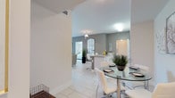 This single-floor residence is designed with a clean, contemporary aesthetic defined by light-toned tile flooring, neutral wall colors, and an open layout that connects the primary living spaces seamlessly. The kitchen serves as a central hub, featuring white cabinetry, granite countertops, white appliances, and a peninsula with bar seating — ideal for casual dining. The adjoining dining area accommodates a glass-top table, while the living room offers access to a glazed sliding door that invites natural light and outdoor views.

The primary bedroom is generously proportioned, benefiting from dual windows with outdoor greenery views, and connects to a spacious walk-in closet outfitted with wire shelving and hanging rails. The second bedroom is equally comfortable, featuring natural light through a vertical-blind window. Both bathrooms are finished with granite-topped vanities, wood-toned cabinetry, large-format tile flooring, and full tub-shower combinations. A dedicated in-unit laundry area houses stacked washer and dryer units, adding everyday convenience. The overall atmosphere is bright, functional, and consistently finished throughout.