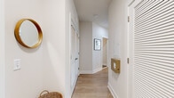 This two-bedroom, three-bathroom residence in Baltimore, MD offers a thoughtfully designed single-level layout with a clean, contemporary aesthetic throughout. Light wood-tone flooring extends across the main living areas, anchoring a bright, neutral palette of white and warm beige tones.

The open kitchen is a standout feature, equipped with stainless steel appliances, white quartz countertops, a subway tile backsplash, and a combination of white upper cabinets and warm wood-grain lower cabinets. A kitchen island provides additional prep and dining space, while pendant lighting adds a modern touch.

The adjacent dining area benefits from floor-to-ceiling windows that frame urban views and draw in generous natural light. The living room continues this window-forward design, creating an airy, well-lit atmosphere ideal for everyday living.

The primary bedroom features large windows with city views and direct access to an en-suite bathroom, which includes a glass-enclosed walk-in shower, wood-tone vanity, and tile flooring. The second bedroom is equally well-appointed. A third full bathroom features a tub-shower combination and matching modern finishes. A light-filled hallway with louvered closet doors completes the layout.