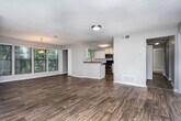 Located at 3400 Winterset Pkwy SE in Marietta, Georgia, this single-floor residence offers a well-designed, open-concept layout with consistent hardwood-style flooring flowing through the main living areas. The spacious living room is bathed in natural light from large windows overlooking a private balcony deck, creating a bright and welcoming atmosphere. A secondary living or family room features a tile-surround fireplace and closet, adding warmth and character to the space. The dining area is highlighted by a stylish pendant light fixture and a wall of windows with vertical blinds, framing views of lush greenery outside. The kitchen is thoughtfully appointed with white shaker cabinetry, dark countertops, a white subway tile backsplash, and a full suite of stainless steel appliances including a gas range, built-in microwave, and dishwasher. Two well-proportioned bedrooms feature plush carpet flooring and natural light from exterior-facing windows. The bathrooms are finished with white cabinetry, clean countertops, and tiled tub-shower combinations, maintaining a cohesive, updated aesthetic throughout. This residence combines functional design with modern finishes in a comfortable Marietta setting.