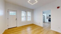 Located at 718 E Linwood Blvd in Kansas City, Missouri, this thoughtfully designed one-bedroom, one-bathroom unit offers a clean, modern aesthetic across a well-utilized single floor. Light-toned hardwood-style flooring runs consistently throughout the space, complementing the crisp white walls and creating a bright, cohesive feel.

The open living area welcomes natural light through multiple windows fitted with blinds, and features a striking geometric hexagonal pendant light fixture overhead. The kitchen is well-appointed with white shaker-style cabinetry, dark countertops, a white subway tile backsplash, and a full suite of stainless steel appliances including a refrigerator, range, microwave, and dishwasher. A dedicated laundry area with a stacked washer and dryer unit adds convenient in-unit functionality.

The bedroom is a comfortable, well-proportioned room with continued hardwood-style flooring, dual windows for natural light, and access to a closet. The bathroom is finished with a mosaic tile floor, large-format stone-look wall tiles surrounding the tub and shower, and a modern wood-toned vanity with brushed hardware. A small window provides ventilation and additional natural light. The overall ambiance is clean, contemporary, and move-in ready.