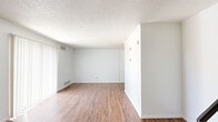 This two-story home in El Paso, Texas offers a practical and well-organized layout spread across two floors. The main level features an open living room with rich hardwood-style flooring, crisp white walls, and a sliding glass door dressed with vertical blinds that allows abundant natural light to fill the space. A staircase with a decorative iron railing connects the two levels. The kitchen is efficiently designed with white cabinetry, white countertops, a double-basin sink, and white appliances including a range and refrigerator, all complemented by hardwood-style flooring. A full bathroom on this floor includes a tiled tub-shower surround with marble-style tile and hardwood-style flooring. Upstairs, two carpeted bedrooms each feature ceiling fans with light fixtures, windows with blinds that bring in natural light, and a clean, neutral color palette. The spacious primary bedroom offers generous room to accommodate various furniture arrangements. A second full bathroom with a clean, minimalist design serves the upper level. Two closets provide additional storage throughout the home. The textured ceilings, consistent neutral tones, and functional layout throughout make this a comfortable and move-in ready residence.