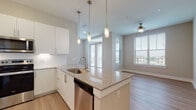 Located on W Broade Street in Leander, Texas, this single-floor residence offers a well-designed, contemporary layout with a clean, modern aesthetic throughout. The open-concept kitchen serves as the centerpiece of the living area, featuring a large granite-topped island with a stainless steel sink and pendant lighting overhead. White shaker-style cabinetry lines the walls, complemented by a full suite of stainless steel appliances including a French door refrigerator, electric range, built-in microwave, and dishwasher. Light wood-look flooring flows throughout the main living areas, adding warmth to the neutral color palette. The spacious living area benefits from large windows and a glass-panel door that fills the room with natural light and provides outdoor views, while a ceiling fan adds comfort overhead. The bedrooms are carpeted and well-lit by large windows with blinds. Two bathrooms serve the residence — one featuring a walk-in glass-enclosed shower with granite vanity, and the other offering a full tub-shower combo with matching granite countertops. A dedicated laundry room with washer and dryer hookups adds everyday convenience. The entry features a smart lock and crisp white panel doors throughout, tying together the space's modern, move-in-ready appeal.
