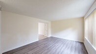 Located at 73 Barrett St in Northampton, MA, this two-story, three-bedroom, two-bathroom home offers a well-organized layout spread evenly across two floors. The main level features two distinct living areas with light gray laminate wood flooring, neutral cream-toned walls, and a textured ceiling. Large windows fitted with vertical blinds allow ample natural light to fill the spaces. The dining room is finished with light ceramic tile flooring, a classic chandelier, and a generous window overlooking the exterior. The kitchen is equipped with white shaker-style cabinetry, white countertops, stainless steel appliances including a gas range, built-in microwave, and dishwasher, along with a window above the counter. A staircase with wood handrail connects the two floors. The upper level hosts the three bedrooms, each carpeted and featuring windows with vertical blinds that bring in natural light and outdoor views. The primary bedroom is a well-proportioned space with a wall-mounted HVAC unit. The bathrooms are clean and functional, with one featuring a pedestal sink, a soaking tub with shower, wood-look tile flooring, and a window for natural ventilation. A hallway connects the upper-level rooms efficiently, completing this practical and well-lit home.
