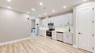 Located at 90 N Sawn St in Albany, NY, this thoughtfully designed one-bedroom, one-bathroom unit offers a compact yet highly functional layout with modern finishes throughout. Light-toned hardwood-style flooring flows seamlessly across the entire space, complementing the neutral warm-beige walls and crisp white trim.

The kitchen is a standout feature, boasting floor-to-ceiling white shaker cabinetry with matte black hardware, a light quartz countertop, and a full suite of stainless steel appliances including a range, over-the-range microwave, dishwasher, and refrigerator. A glass tile backsplash adds a clean, polished touch, while an in-unit washer and dryer are conveniently integrated into the kitchen area.

The bedroom is a bright, comfortable retreat with a wide multi-pane window that frames views of the Albany streetscape, filling the room with natural light. A set of sliding closet doors provides ample storage, and a wall-mounted mini-split unit ensures year-round climate control.

The bathroom features upscale finishes, including large-format stone-look floor tiles, dramatic marble-veined wall tile, a warm wood-toned vanity with gold hardware, and a contemporary multi-bulb vanity light fixture, creating a spa-like atmosphere. Recessed lighting throughout the unit enhances the modern, clean aesthetic of this well-appointed Albany residence.