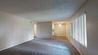 Located at 16211 Parkside Ln in Huntington Beach, CA, this single-story, three-bedroom, one-bathroom home offers a practical and comfortable layout. The open living area is generously sized, featuring plush wall-to-wall carpet, a textured ceiling, and a neutral color palette that creates a bright, welcoming atmosphere. A ceiling fan adds comfort to the adjoining dining area, which transitions seamlessly to the kitchen via wood-look flooring. The galley-style kitchen is well-appointed with white cabinetry, dark granite countertops, matching white appliances including a gas range and built-in microwave, and a stainless steel sink with a dishwasher — all illuminated by overhead lighting. The three bedrooms are carpeted and offer ample wall space; the spacious primary bedroom includes a sliding-door closet with built-in rod storage. The full bathroom features wood-look flooring, a full tub-shower combination, a white vanity with a stone-topped countertop, a large mirror, and a small privacy window for natural light. A hallway connects the main living areas to the bedrooms and bathroom, completing the efficient single-floor floor plan.