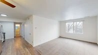 This single-floor residence offers a clean, functional layout designed for comfortable everyday living. The spacious main living area seamlessly transitions between wood-look flooring near the entry and plush carpeting in the lounge zone, creating a warm and inviting atmosphere. A large window floods the living space with natural light and frames views of mature trees outside, adding a touch of nature to the interior. A ceiling fan provides both comfort and ambient lighting in the combined living and dining area.

The kitchen is thoughtfully updated with white shaker-style cabinetry, granite-look countertops, a white subway tile backsplash, and a full suite of stainless steel appliances, including a range, microwave, dishwasher, and refrigerator. Wood-look flooring continues throughout the kitchen, complementing the crisp, modern finishes.

The bedrooms are carpeted and bathed in natural light through windows fitted with horizontal blinds, offering a quiet and restful environment. The bathroom features large-format neutral tile surrounding the tub and shower, paired with a white vanity, mirror, and clean, contemporary fixtures. Throughout the unit, bright white walls and simple, timeless finishes contribute to an overall sense of openness and ease.
