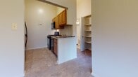 Located at 5006 Windsor Mill Rd in Baltimore, Maryland, this single-floor unit offers a functional and well-organized layout designed for comfortable everyday living. The kitchen is equipped with warm wood cabinetry, a gas range, built-in microwave, and a granite-style countertop peninsula that serves as a natural divider between the kitchen and adjacent living areas. Tile flooring in the kitchen transitions smoothly into the carpeted living spaces. A dedicated shelving nook near the kitchen provides convenient additional storage. The spacious living and dining area features plush carpeting, a pendant light fixture, and large windows that invite abundant natural light and views of the surrounding greenery. The front entry door and side windows further enhance the bright, airy atmosphere of this open zone. The bedrooms are generously sized, each featuring soft carpeting and closets with built-in hanging rods for organized storage. Windows in the bedrooms bring in natural light and outdoor views. The overall layout is efficient and cohesive, with neutral tones on the walls and flooring throughout, creating a clean and versatile backdrop suited to a variety of living arrangements.