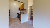 Located at 5006 Windsor Mill Rd in Baltimore, Maryland, this single-floor unit offers a functional and well-organized layout designed for comfortable everyday living. The kitchen is equipped with warm wood cabinetry, a gas range, built-in microwave, and a granite-style countertop peninsula that serves as a natural divider between the kitchen and adjacent living areas. Tile flooring in the kitchen transitions smoothly into the carpeted living spaces. A dedicated shelving nook near the kitchen provides convenient additional storage. The spacious living and dining area features plush carpeting, a pendant light fixture, and large windows that invite abundant natural light and views of the surrounding greenery. The front entry door and side windows further enhance the bright, airy atmosphere of this open zone. The bedrooms are generously sized, each featuring soft carpeting and closets with built-in hanging rods for organized storage. Windows in the bedrooms bring in natural light and outdoor views. The overall layout is efficient and cohesive, with neutral tones on the walls and flooring throughout, creating a clean and versatile backdrop suited to a variety of living arrangements.