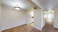 Located at 735 Marlan Ave. in Reynoldsburg, Ohio, this single-floor unit offers a straightforward and functional layout designed for comfortable everyday living. The living area is generously sized, featuring warm wall-to-wall carpeting, neutral beige walls, and a textured ceiling with a central pendant light fixture. A sliding glass door fitted with vertical blinds fills the space with natural light and provides outdoor access. The living area connects openly to a dining space, which flows directly into the galley-style kitchen. The kitchen is efficiently designed with white cabinetry, dark laminate countertops, tile flooring, and white appliances including a refrigerator, electric range, and dishwasher. A door off the kitchen leads to a dedicated laundry area with shelving and additional storage. The bedroom is a well-proportioned room with carpet flooring, two windows that invite natural light, and access to a vanity area with a sink. A separate walk-in closet offers ample storage. The bathroom features tile flooring, a full-size tub and shower combo, and clean white fixtures. Throughout the unit, the consistent use of neutral tones and textured ceilings creates a cohesive and understated aesthetic.