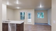 Located in Salem, Oregon, this well-designed one-bedroom, one-bathroom unit offers a smart, efficient layout with contemporary finishes throughout. The open-concept kitchen and living area form the heart of the space, where light wood-look vinyl plank flooring, neutral warm-toned walls, and recessed lighting create a clean, welcoming atmosphere. A wall-mounted mini-split unit provides efficient climate control in the living area, which also features a private exterior door and multiple windows offering views of the surrounding greenery.

The kitchen is a standout feature, boasting rich dark-walnut cabinetry, granite-style countertops, and a full suite of stainless steel appliances including a range, microwave, and refrigerator. A peninsula with an integrated sink and breakfast bar connects the kitchen seamlessly to the living space.

The bedroom is carpeted for comfort and features a window with pleasant outdoor views, along with generous closet space including both a reach-in and walk-in closet for ample storage.

The bathroom continues the consistent design language with matching dark cabinetry, granite-style countertops, and wood-look flooring, with convenient access to the walk-in closet. The unit's cohesive, modern aesthetic and functional layout make it a practical and attractive space.