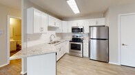 Located at 1515 Seventh St S in Waite Park, Minnesota, this single-floor unit offers a thoughtfully updated interior with a clean, neutral palette throughout. The kitchen stands out as a clear highlight, showcasing white shaker-style cabinetry, granite-look countertops, a classic subway tile backsplash, and a full suite of stainless steel appliances including a refrigerator, range, and over-the-range microwave. Light wood-tone flooring ties the kitchen seamlessly into the open dining and living areas. The dining space is accented by a modern chandelier, while sliding glass doors flood the living room with natural light and provide views of the surrounding greenery. A carpeted bedroom offers a quieter, softer retreat, complete with a window that brings in additional natural light and a baseboard heating unit for year-round comfort. The bathroom is efficiently designed with a full tub-shower combo, a curved shower rod, a vanity with mirror, and neutral finishes throughout. The textured ceilings and warm beige tones carry a consistent, cohesive feel across all spaces, creating a comfortable and functional home in a convenient Waite Park location.