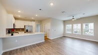 Located at Windsor Cay Blvd in Clermont, Florida, this two-story home offers a thoughtfully designed layout spread across two levels. The main floor welcomes you with an open-concept kitchen and living area finished with light wood-look flooring and a neutral color palette. The kitchen is well-appointed with white shaker-style cabinetry, a gray tile backsplash, stainless steel appliances including a refrigerator with ice maker, range, microwave, and dishwasher, and a bright white countertop island with a undermount sink. The living area extends comfortably from the kitchen, featuring a ceiling fan and windows that invite natural light. Carpeted stairs with a white handrail lead to the upper level, where both bedrooms are situated. Each bedroom features wood-look flooring, ceiling fans, and multiple windows offering outdoor views. The primary bedroom includes a spacious walk-in closet with built-in wire shelving and a natural light window. The bathrooms are clean and functional, with one featuring a tiled tub-shower combination. A dedicated laundry room on the upper level houses a full-size washer and dryer. The home combines practical functionality with a bright, modern aesthetic throughout.