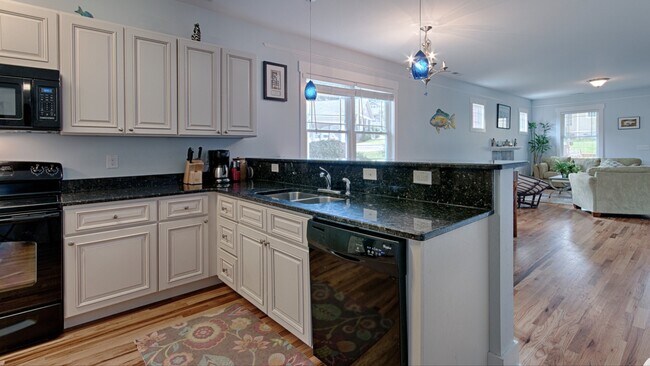 Cocina con encimeras de granito, barra de desayuno, lavavajillas e iluminación colgante. - 144 Estelle Park Dr