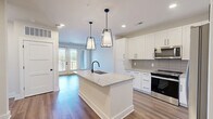 Located in Marietta, GA, this thoughtfully designed two-bedroom, one-bathroom residence offers a clean, modern aesthetic throughout its single-floor layout. The open-concept kitchen and living area serves as the heart of the home, anchored by a large central island with granite countertops, an undermount sink, and matte black fixtures. White shaker cabinetry, a gray tile backsplash, and stainless steel appliances—including a refrigerator, range, microwave, and dishwasher—complete the kitchen. Stylish pendant lighting adds a contemporary touch, while hardwood-style flooring flows throughout the main living areas. The two bedrooms are carpeted and bathed in natural light from large windows with exterior views. The primary bedroom includes a spacious walk-in closet with built-in wire shelving. The bathroom features a double-vanity with granite countertops, white cabinetry, matte black hardware, light tile flooring, and a glass-enclosed walk-in shower. Additional conveniences include a dedicated laundry space, a utility room, a hallway connecting the rooms, and a private balcony accessible from the living area. Three closets provide ample storage throughout the residence.