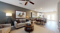 Located in Cumming, GA, this two-story home offers a thoughtfully designed open-concept layout across two levels. The main floor seamlessly connects the living, dining, and kitchen areas, creating an inviting and functional space. The living room features a ceiling fan, recessed lighting, and a warm neutral color palette, anchored by an accent wall in a rich taupe-gray tone. Large framed artwork adds visual character throughout.

The kitchen is outfitted with white shaker cabinetry, granite countertops, stainless steel appliances — including a refrigerator, range, microwave, and dishwasher — and a subway tile backsplash. Pendant lighting illuminates the peninsula, which offers bar seating and flows directly into the dining area. French doors in the kitchen provide access to the outdoors and fill the space with natural light.

The entryway on the main level is welcoming and open, featuring a staircase leading to the upper floor. Upstairs, the bedrooms offer plush carpeting, natural light from multiple windows, and distinctive accent walls — one in a deep navy blue, another in a warm taupe. The bathroom includes white cabinetry, granite countertops, and wood-look flooring. Consistent light wood-look flooring throughout the main level ties the home together with a cohesive, modern aesthetic.