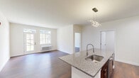 This thoughtfully designed 2-bedroom, 1-bathroom residence in Swiftwater, PA offers a clean, modern aesthetic throughout its single-floor layout. Rich hardwood-style flooring flows continuously through every room, creating a cohesive and inviting atmosphere.

The open-concept kitchen and living area serves as the heart of the home. The kitchen is outfitted with dark espresso shaker cabinets, granite countertops, a white subway tile backsplash, and stainless steel appliances including a refrigerator with ice maker and a range. A large central island with an undermount sink and pendant lighting provides additional prep space and casual seating.

The living area features large windows and a glass-paneled exterior door that floods the space with natural light and offers views of the surrounding greenery. Both bedrooms are generously sized with bright windows and wall-unit climate control. The spacious primary bedroom includes access to a walk-in closet with built-in wire shelving for organized storage.

The full bathroom is finished with a white quartz vanity, an illuminated mirror, wood-tone flooring, and accessibility-friendly grab bars alongside a marble-surround tub and shower. A dedicated laundry room houses a full-size Whirlpool front-load washer and dryer. Two closets provide ample storage throughout the residence.