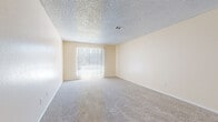 This single-floor, 3-bedroom, 2-bathroom residence offers a thoughtfully arranged layout designed for comfortable everyday living. The main living area features plush wall-to-wall carpeting, warm neutral-toned walls, a textured ceiling, and a sliding glass door fitted with vertical blinds that invite natural light and provide access to the outdoors. Adjacent to the living space, a transition area connects seamlessly to the rest of the home, where wood-style flooring continues into the kitchen. The kitchen is outfitted with warm oak cabinetry, light countertops, a double-basin sink beneath a window overlooking the exterior, and white appliances including a dishwasher — providing ample storage and workspace. Each of the three bedrooms is carpeted and bathed in natural light from well-placed windows. One bedroom features a built-in closet with integrated shelving, offering generous organizational space. The two bathrooms are finished with stone-look tile flooring. One bathroom includes a vanity with a granite-style countertop, an oval undermount sink, a large mirror, and a tub-shower combination. The second bathroom also features a full tub-shower setup with clean white tile surround. Together, these spaces create a practical and comfortable home.