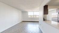Located on the 9th floor at 55 Park Street East in Mississauga, this well-appointed one-bedroom, one-bathroom unit offers a practical and comfortable layout across a single floor. The open living area features classic parquet flooring and is bathed in natural light through a large picture window, which also frames pleasant outdoor views. A baseboard heating system runs along the exterior wall, ensuring year-round comfort. The living space connects seamlessly to the kitchen via a built-in pass-through opening, enhancing the sense of openness. The kitchen is equipped with dark-toned cabinetry, a stainless steel refrigerator, and tile flooring, offering a functional cooking environment. The bedroom is a calm and airy retreat finished with light hardwood flooring, a large window with outdoor views, and a full-width sliding door closet providing ample storage. The bathroom features a clean, tiled wet area surrounding a full soaker tub and shower, with warm beige tile work accented by white horizontal banding for a tidy, classic finish. Throughout the unit, crisp white walls and clean baseboards create a bright, neutral palette. A textured ceiling is consistent throughout, adding a layer of character to this efficiently designed urban residence.