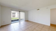 Located at 693 Wymore Road in Altamonte Springs, Florida, this two-bedroom, two-bathroom single-floor residence offers a practical and comfortable layout. The open-concept living and dining area is finished with large-format tile flooring and features a sliding glass door with vertical blinds, allowing natural light to pour in while providing direct access to the outdoors. Track lighting accents the transition into the kitchen area, which is well-appointed with warm wood cabinetry, dark granite-style countertops, a mosaic tile backsplash, a stainless steel dishwasher, and a window above the sink that lets in additional natural light. A dedicated dining room connects the kitchen and main living spaces. The hallway, finished with wood-look laminate flooring, leads to both bedrooms and bathrooms. The bedrooms feature the same wood-look flooring and bright white walls, with windows providing natural light and ample closet storage—four closets are distributed throughout the unit. Both bathrooms are identically appointed with tile flooring, warm wood vanities, white countertops, and a full tub-shower combination. The textured ceilings and clean white walls throughout give the residence a bright, neutral aesthetic suited for a variety of interior styles.