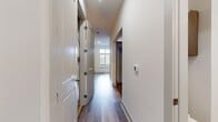 This 420 square foot apartment offers a thoughtfully designed living space on a single floor. The kitchen is a standout feature, boasting a sleek, modern design with wood-grain cabinetry, granite countertops, and a full suite of stainless steel appliances including a French door refrigerator, built-in microwave, dishwasher, and electric range. The backsplash features clean, white subway tiles that complement the overall aesthetic.

The bathroom is equally impressive, with a glass-enclosed shower, large format beige tiles, and a vanity with granite countertop matching the kitchen. The toilet is strategically placed for privacy.

Throughout the apartment, wood-look vinyl flooring adds warmth and durability. The open concept layout maximizes the use of space, with the kitchen flowing seamlessly into the living area. High ceilings and recessed lighting contribute to a sense of spaciousness.

A hallway connects the main living area to the bathroom, providing a sense of separation between spaces. The apartment's design prioritizes functionality without sacrificing style, making efficient use of the 420 square feet to create a comfortable and contemporary living environment.