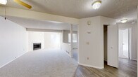 This single-floor residence in Westminster, Colorado offers a practical and comfortable layout encompassing one bedroom and two full bathrooms. The open living room is a standout feature, highlighted by a classic fireplace with tile surround, plush wall-to-wall carpet, and a textured ceiling. Natural light flows in through multiple windows, creating a bright and inviting atmosphere. The living area extends into a secondary room—visible through a wide pass-through opening—that offers flexible use as a dining space or office, with its own window providing additional light.

The kitchen is well-appointed with warm wood-toned cabinetry offering generous upper and lower storage, light-colored laminate countertops, wood-look vinyl flooring, and white appliances including a full-size refrigerator and range.

The spacious primary bedroom features plush carpeting, a closet, and direct access to an en-suite bathroom. Both bathrooms include tub/shower combinations with white tile surrounds and clean, neutral finishes. One bathroom features wood-look flooring and a vanity with stone-look countertop. A ceiling fan in the entryway area and ample closet space complete this well-organized home.
