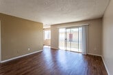 Located at 1021 W B St in Ontario, California, this single-floor unit offers a well-organized layout with a thoughtful mix of finishes throughout. The living area is a bright, open space featuring rich hardwood-style flooring, neutral-toned walls, and a textured ceiling. A large sliding glass door floods the room with natural light and opens to a balcony, providing outdoor views of the surrounding neighborhood. The kitchen is efficiently designed with white cabinetry, dark granite countertops, a sink, and a peninsula counter with a beadboard surround — ideal for casual dining or meal prep. The hardwood-style flooring continues seamlessly from the living area into the kitchen. The bedrooms are carpeted for added comfort and each features mirrored sliding closet doors that enhance the sense of space. Windows in the bedrooms allow for natural light and views of the surrounding greenery. Two bathrooms serve the unit, both finished with granite-topped vanities, white cabinetry, hardwood-style flooring, and glass-enclosed showers. One bathroom also includes a shower-tub combination. The textured ceilings are consistent throughout, lending a cohesive character to the space. Overall, the unit presents a clean, functional, and comfortable living environment in a residential Ontario neighborhood.