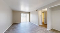 This 2-bedroom, 1-bathroom unit offers a thoughtfully designed single-floor layout that maximizes functionality and comfort. The open living area features wood-look flooring in a light gray tone, neutral-painted walls, and a sliding glass door that fills the space with natural light while providing access to an outdoor area. The kitchen is well-equipped with white cabinetry, granite countertops, a stainless steel sink, and a full suite of stainless steel appliances including a refrigerator, range, and microwave. A tray ceiling detail adds architectural interest to the kitchen area. Both bedrooms are comfortably sized, each featuring wood-look flooring, neutral walls, and window blinds that allow for natural light control. The primary bedroom includes a sliding door leading to a walk-in closet with built-in shelving, offering generous storage. A dedicated walk-in pantry with floor-to-ceiling shelving is an additional storage highlight. The bathroom features a granite-topped vanity, a full tub-shower combination, and a large mirror. A connecting hallway ties all rooms together efficiently, completing this clean and modern living space.