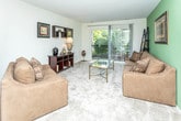 Located at 3200 S Adams Rd in Auburn Hills, Michigan, this single-floor residence offers a well-organized layout designed for comfortable everyday living. The open-concept living and dining area serves as the heart of the home, featuring plush carpeting, neutral tones, and an accent wall that adds a touch of color. A sliding glass door floods the living space with natural light and provides direct access to a private balcony overlooking lush greenery — a standout feature that brings the outdoors in. The galley-style kitchen is efficiently designed with ample white cabinetry, generous counter space, white appliances including a stove, refrigerator, and built-in microwave, and tile flooring for easy maintenance. The two bedrooms are carpeted and bright, each with windows that frame tranquil outdoor views, offering a calm and restful atmosphere. The full bathroom is clean and functional, featuring a tiled tub-shower combination, a vanity with a wide mirror, and tile flooring. A closet visible from the main living area provides convenient storage. Throughout the residence, the consistent use of light, neutral finishes and soft carpeting creates a cohesive, understated aesthetic that is both inviting and practical.