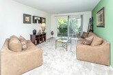Located at 3200 S Adams Rd in Auburn Hills, Michigan, this single-floor residence offers a well-organized layout designed for comfortable everyday living. The open-concept living and dining area serves as the heart of the home, featuring plush carpeting, neutral tones, and an accent wall that adds a touch of color. A sliding glass door floods the living space with natural light and provides direct access to a private balcony overlooking lush greenery — a standout feature that brings the outdoors in. The galley-style kitchen is efficiently designed with ample white cabinetry, generous counter space, white appliances including a stove, refrigerator, and built-in microwave, and tile flooring for easy maintenance. The two bedrooms are carpeted and bright, each with windows that frame tranquil outdoor views, offering a calm and restful atmosphere. The full bathroom is clean and functional, featuring a tiled tub-shower combination, a vanity with a wide mirror, and tile flooring. A closet visible from the main living area provides convenient storage. Throughout the residence, the consistent use of light, neutral finishes and soft carpeting creates a cohesive, understated aesthetic that is both inviting and practical.