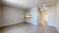 This single-floor residence offers a thoughtfully laid-out living space with a clean, modern aesthetic throughout. The open living area is finished with durable wood-look plank flooring in a warm gray tone, complemented by neutral walls and crisp white baseboards that create a bright, airy atmosphere. A ceiling fan provides both function and style overhead.

The kitchen is accessible via a convenient pass-through counter with a dark ledge that opens to the living area, making it ideal for casual dining or entertaining. Inside, the kitchen is well-equipped with white cabinetry, gray countertops, a stainless steel gas range with an overhead exhaust hood, a stainless steel sink, and a classic white subway tile backsplash that adds a timeless touch.

The entryway features the same wood-look flooring and is accented by an exposed brick-style wall framing the front door, with vertical blinds allowing light to filter in from a large window.

The bedroom offers a comfortable, carpeted retreat with soft gray pile underfoot, neutral walls, and a closet with sliding doors — providing generous storage space.

The bathroom is finished with a full-size soaking tub and shower combination, sleek chrome fixtures, and wood-look tile flooring, offering a clean and functional design. Together, these spaces form a cohesive and move-in ready home.