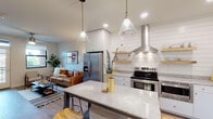 Located at 1211 East 7th Street in Tulsa, Oklahoma, this single-floor residence blends modern design with warm, inviting finishes. The kitchen serves as a true centerpiece, showcasing shiplap-accented walls, white cabinetry, granite countertops, and a striking island with seating. Stainless steel appliances — including a range with a statement hood vent, refrigerator, and dishwasher — are complemented by open wooden shelving and pendant lighting, creating a functional yet stylish cooking space. The kitchen flows seamlessly into the living area, where large windows invite natural light and ceiling fans add comfort. The living room offers a relaxed atmosphere with views to the outdoors. The bedrooms feature plush carpeting, ceiling fans, and well-sized windows fitted with roller shades for privacy and light control. The bathroom is finished with classic hexagonal tile flooring, a floating white vanity with granite countertops, subway tile in the shower area, and bright vanity lighting. A walk-in closet is conveniently accessible from the bathroom. Throughout the residence, wood-look flooring, neutral tones, and thoughtful details create a cohesive, contemporary aesthetic that is both functional and visually appealing.
