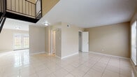 This two-story, 2-bedroom, 1.5-bathroom home offers a well-organized layout across two distinct levels, connected by a bold black metal staircase that serves as a striking architectural focal point in the main living area. Light beige walls and large-format polished tile flooring run throughout, lending a clean, cohesive look to the entire home.

The kitchen is a standout space, featuring a U-shaped configuration with dark cabinetry, dark granite-style countertops, tile backsplash, and stainless steel appliances including a dishwasher. A peninsula adds additional counter space and visual definition, while a sliding glass door provides direct access to the outdoors, filling the area with natural light.

The main living area is open and airy, benefiting from the dramatic vertical height created by the two-story design. Both bedrooms are located on the upper level and offer comfortable, well-proportioned spaces with large windows that invite natural light. Ceiling fans are present in the bedrooms for added comfort.

The bathroom areas feature tile flooring and light-toned vanities with granite-style countertops. Closet space is thoughtfully incorporated throughout the home. The textured ceilings add subtle detail, while the neutral color palette throughout creates a versatile and move-in ready environment.