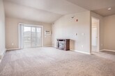 Located at W6908 Walden Pl in Holmen, WI, this well-appointed one-bedroom, one-bathroom residence offers a thoughtfully designed single-floor layout. The open-concept kitchen and living area serves as the heart of the home, where rich dark wood cabinetry, granite countertops, and a large center island with a double sink create a functional and stylish kitchen. Stainless steel appliances — including a range, microwave, and French door refrigerator — complement the space, which transitions seamlessly from hardwood-style flooring into the carpeted living area. The living room features vaulted ceilings that enhance the sense of openness, with a sliding glass door providing access to a private balcony with outdoor views. The generously sized bedroom offers plush carpeting, a ceiling fan, a natural light-filled window, and two closets for ample storage. The full bathroom is finished with tile flooring, a dark wood vanity, and clean white fixtures. A dedicated laundry room adds everyday convenience. Baseboard heating throughout ensures year-round comfort, rounding out this efficient and attractively finished home.