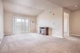 Located at W6908 Walden Pl in Holmen, WI, this well-appointed one-bedroom, one-bathroom residence offers a thoughtfully designed single-floor layout. The open-concept kitchen and living area serves as the heart of the home, where rich dark wood cabinetry, granite countertops, and a large center island with a double sink create a functional and stylish kitchen. Stainless steel appliances — including a range, microwave, and French door refrigerator — complement the space, which transitions seamlessly from hardwood-style flooring into the carpeted living area. The living room features vaulted ceilings that enhance the sense of openness, with a sliding glass door providing access to a private balcony with outdoor views. The generously sized bedroom offers plush carpeting, a ceiling fan, a natural light-filled window, and two closets for ample storage. The full bathroom is finished with tile flooring, a dark wood vanity, and clean white fixtures. A dedicated laundry room adds everyday convenience. Baseboard heating throughout ensures year-round comfort, rounding out this efficient and attractively finished home.