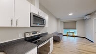 Located at 225 Innovation Way in Scarborough, Maine, this efficiently designed single-floor unit offers a thoughtfully laid-out living space across three distinct areas. Light natural wood-look flooring runs throughout, lending warmth and visual continuity to the entire unit.

The open-plan kitchen and living area forms the heart of the space. The kitchen is outfitted with crisp white cabinetry extending to the ceiling for ample storage, dark granite-style countertops, a stainless steel refrigerator, electric range with over-the-range microwave, and a dishwasher — all finished in a cohesive modern aesthetic. The adjoining living area receives natural light through a large window fitted with a roller shade, creating a bright and comfortable setting.

The bedroom is a quiet, minimal retreat featuring a wall-mounted ductless mini-split HVAC unit for individualized climate control and a high clerestory window that allows natural light while maintaining privacy. The light-toned walls and wood flooring carry the clean design language of the rest of the unit.

The bathroom is efficiently appointed with a walk-in shower, a toilet, and a vanity, all set against light flooring and neutral walls. A small window above provides ventilation and natural light. The unit's overall design is clean, modern, and move-in ready, suited for those seeking a practical yet stylish living environment in Scarborough, ME.