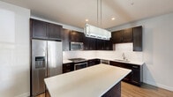 Located at 31 East Ogden Avenue in La Grange, IL, this two-bedroom, two-bathroom residence offers a well-designed single-floor layout with a thoughtful mix of modern finishes and functional spaces. The open-concept kitchen is a standout feature, showcasing dark espresso cabinetry, a classic white subway tile backsplash, stainless steel appliances including a gas range, built-in microwave, dishwasher, and French door refrigerator, all centered around a large kitchen island with a crisp white countertop and pendant lighting overhead. The kitchen flows seamlessly into the living area, which features warm wood-look flooring and vaulted ceilings that enhance the sense of openness. Both bedrooms are carpeted and receive natural light through large windows with outdoor views. The primary bedroom is generously sized and complemented by a walk-in closet with wire shelving. Four closets total provide ample storage throughout. The bathrooms are finished with light tile flooring, dark vanity cabinetry, white countertops, and chrome fixtures; one bathroom includes a soaking tub with full subway tile surround. Additional conveniences include an in-unit laundry area and a private balcony. The overall aesthetic is clean, contemporary, and move-in ready.