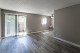 Located at 1000 Pine Ave in Redlands, California, this single-floor unit offers a thoughtfully designed layout with a clean, contemporary aesthetic throughout. Light wood-style flooring runs consistently across the living spaces, complemented by warm beige walls and crisp white baseboards that create a bright, cohesive feel.

The spacious living area features a ceiling fan, a sliding glass door that opens to a private outdoor patio, and an additional window that draws in generous natural light. A second open living or dining area also benefits from patio access via another sliding door, providing excellent indoor-outdoor connectivity.

The galley-style kitchen is well-appointed with white shaker cabinetry, white countertops, and a mosaic tile backsplash. Stainless steel appliances, including a range, refrigerator, and dishwasher, complete the functional cooking space.

The bedroom offers mirrored sliding closet doors with built-in shelving, a window overlooking the exterior, and the same wood-style flooring found throughout. The bathroom includes a white vanity with modern hardware, a combined shower and bathtub, and a high window that allows natural light while maintaining privacy. A textured ceiling is present throughout the unit, adding a classic finishing detail.