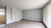 Located at 313 Sunnyside St in Houston, TX, this single-story one-bedroom, one-bathroom home offers a thoughtfully laid-out floor plan with a comfortable and functional living environment. The living room serves as the heart of the home, highlighted by a striking white-painted brick fireplace flanked by built-in shelving — a charming architectural focal point. Light gray laminate flooring and soft blue-gray walls lend a clean, modern aesthetic throughout the main living area. A large sliding glass door floods the space with natural light and provides pleasant views of the greenery outside. The galley-style kitchen is well-appointed with gray cabinetry, marble-look quartz countertops, a stainless steel sink, and stainless steel appliances, including a refrigerator and electric range. Light wood-look flooring completes the kitchen's contemporary feel. The spacious primary bedroom features plush carpeting, a ceiling fan with integrated lighting, a bright window with blinds, and a generous closet with double bi-fold doors offering ample storage. A second closet provides additional storage convenience. The bathroom includes a quartz-topped vanity with gray cabinetry, a tub-shower combo, and wood-look flooring, maintaining the cohesive style found throughout the home.