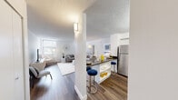 Located at 1317 East St in New Britain, CT, this 2-bedroom, 2-bathroom residence offers a thoughtfully designed single-floor layout that maximizes comfort and functionality. The open-concept living and kitchen area serves as the heart of the home, where a bright, airy living room with large windows and abundant natural light flows seamlessly into a sleek kitchen. The kitchen features white cabinetry with dark countertops, stainless steel appliances including a refrigerator, dishwasher, and range, plus a breakfast bar with seating. Wood-style flooring runs throughout the space, adding warmth and visual continuity. The spacious primary bedroom is generously sized and bathed in natural light from large windows, offering ample room for a full furniture arrangement. The second bedroom is equally comfortable, with access to a walk-in closet. Both bathrooms are clean and functional, featuring white vanities with under-cabinet storage, mirrored medicine cabinets, and warm tile accents. The residence also benefits from six closets throughout, providing exceptional storage. Textured ceilings and crisp white walls create a neutral backdrop that suits a variety of interior styles, contributing to the home's bright and welcoming ambiance.