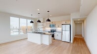 Located at 2820 West Broad Street in Richmond, Virginia, this modern 2-bedroom, 2-bathroom residence offers a thoughtfully designed open-concept layout with contemporary finishes throughout. Light hardwood flooring flows seamlessly across the entire space, lending warmth and cohesion to every room.

The combined kitchen and living area serves as the heart of the home. The kitchen is outfitted with light maple cabinetry, open floating shelves, a white subway tile backsplash, dark granite countertops, and a large central island with an undermount sink — all illuminated by a trio of bold black dome pendant lights. Stainless steel appliances complete this well-appointed culinary space. Large windows flood the area with natural light and frame views of the surrounding cityscape.

Both bedrooms are bright and airy, benefiting from oversized windows that offer expansive views of Richmond's West Broad Street corridor. The primary bedroom includes two closets and generous proportions for comfortable furnishing.

The two bathrooms are finished with granite-topped vanities and light wood cabinetry. One bathroom features a soaking tub with a striking blue vertical tile surround, while the other offers a clean, neutral aesthetic with ample natural light. A connecting hallway provides smooth circulation throughout the residence.