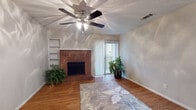 This single-floor residence offers a thoughtfully designed layout with a comfortable blend of classic charm and modern updates. The living room serves as the heart of the home, anchored by a striking full-brick fireplace with a raised hearth and flanked by built-in shelving. Wood-look flooring extends throughout this space, while a ceiling fan with light kit and vertical blinds covering a sliding glass door complete the room. Natural light filters in, adding warmth to the open feel.

Adjacent to the living area, the dining space features additional wood-look flooring, a pendant light fixture, and direct access to the kitchen. The kitchen is well-equipped with rich dark cabinetry, granite-look countertops, a stainless steel dishwasher, a double-basin sink, and an eye-catching mosaic tile backsplash that adds a decorative touch.

The bedrooms are carpeted for comfort and each include ceiling fans with light kits and windows with blinds allowing natural light. The bathrooms are clean and functional — one features a tiled shower-tub combo, while another includes wood-look flooring, a vanity with dark cabinetry, and a shower with curtain. Textured ceilings are present throughout, adding a consistent architectural detail across the entire residence.