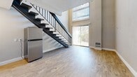 Located at 2886 S Circle Dr in Colorado Springs, CO, this two-story residence offers a well-organized layout across two floors. The main level features an open-concept living area and kitchen, where light wood-style flooring and neutral-toned walls create a clean, modern aesthetic. The kitchen is equipped with white cabinetry, a stainless steel refrigerator, a built-in microwave, and a tile backsplash, seamlessly integrating with the living space. A striking open-riser staircase with a dark metal railing serves as a visual focal point, leading the eye upward to dramatic double-height ceilings and a large window that floods the space with natural light. A sliding glass door on the main level provides additional brightness and outdoor access. The upper floor houses the primary bedroom, which benefits from windows overlooking the living area below, along with wood-style flooring and open railing that maintains the airy, connected feel of the home. Three bathrooms serve the residence; one features a soaking tub with tile surround and grab bar, while another includes a sliding-door shower stall with a white vanity. An additional bathroom on the upper level includes a vessel sink atop granite-style countertops with access to a dedicated closet. Textured ceilings are present throughout, adding character to every room.