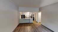 Located at 2900 Reidville Rd in Spartanburg, South Carolina, this single-floor unit offers a practical and functional layout designed for comfortable everyday living. Throughout the space, durable hardwood-style flooring flows seamlessly, complemented by neutral gray walls and textured ceilings that lend a consistent, clean aesthetic.

The living area is open and well-lit, benefiting from natural light streaming through a large window fitted with horizontal blinds. A distinctive semi-open kitchen is separated from the living space by a windowed partition wall, creating a connected yet defined cooking area. The kitchen is equipped with white upper and lower cabinetry, dark granite-style countertops, a stainless steel double-basin sink, a black refrigerator, and a black electric range with an overhead exhaust hood — providing all essential appliances in a compact, efficient arrangement.

The bedroom is a comfortable, private retreat featuring its own window for natural light and ventilation, a ceiling fan with integrated lighting, and the same consistent hardwood-style flooring found throughout the unit. A hallway connects the main living areas to the bedroom and bathroom, contributing to a logical and easy-to-navigate floor plan.

The bathroom includes a combined tub and shower unit, a toilet, and a vanity with dark countertop, all finished in a clean, understated style. A utility area housing a water heater is also present within the unit's footprint.